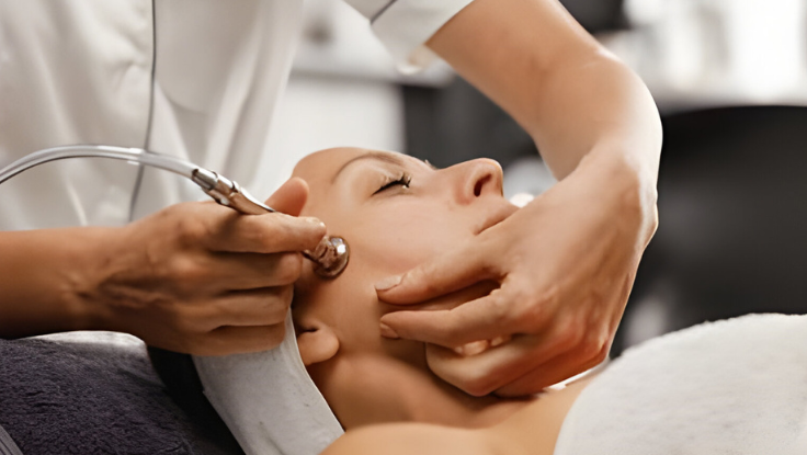 A woman is receiving a microdermabrasion cosmetic facial treatment with a machine at a spa.